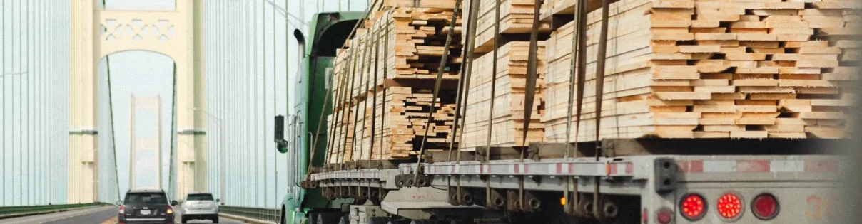 Truck hauling tied down wooden two by fours in the truck bed.