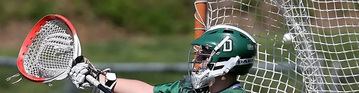 Lacrosse player in green jersey defending the goal with a red-netted stick.