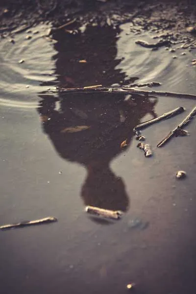 boy looking upon a puddle 