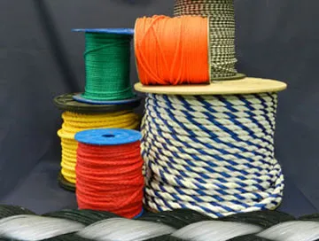 Variety of colorful ropes and cords on spools, including green, orange, yellow, and blue-white twisted rope, displayed against a dark background.