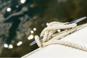 Boat rope tied to cleat with shimmering water in the background