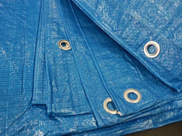 Close-up of a folded blue tarp with metal grommets, showcasing its textured surface and reinforced edges.